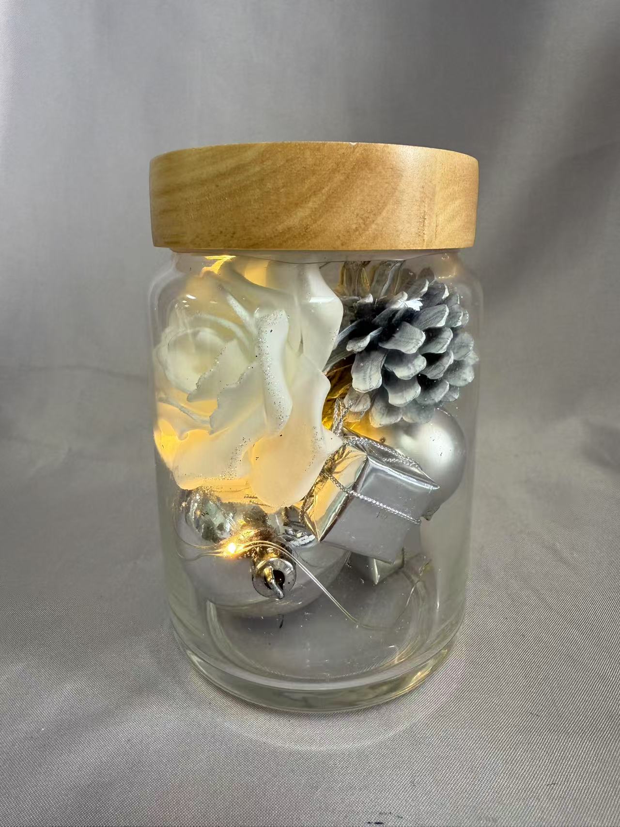 シルバーのトゥインクルワイヤーライトを備えた密閉ガラスジャーの保存された花の花束（AA×2バッテリー駆動）、白いバラ、シルバーベリー、オーブ、ギフトボックス、松ぼっくり、ドライグラスで飾られています