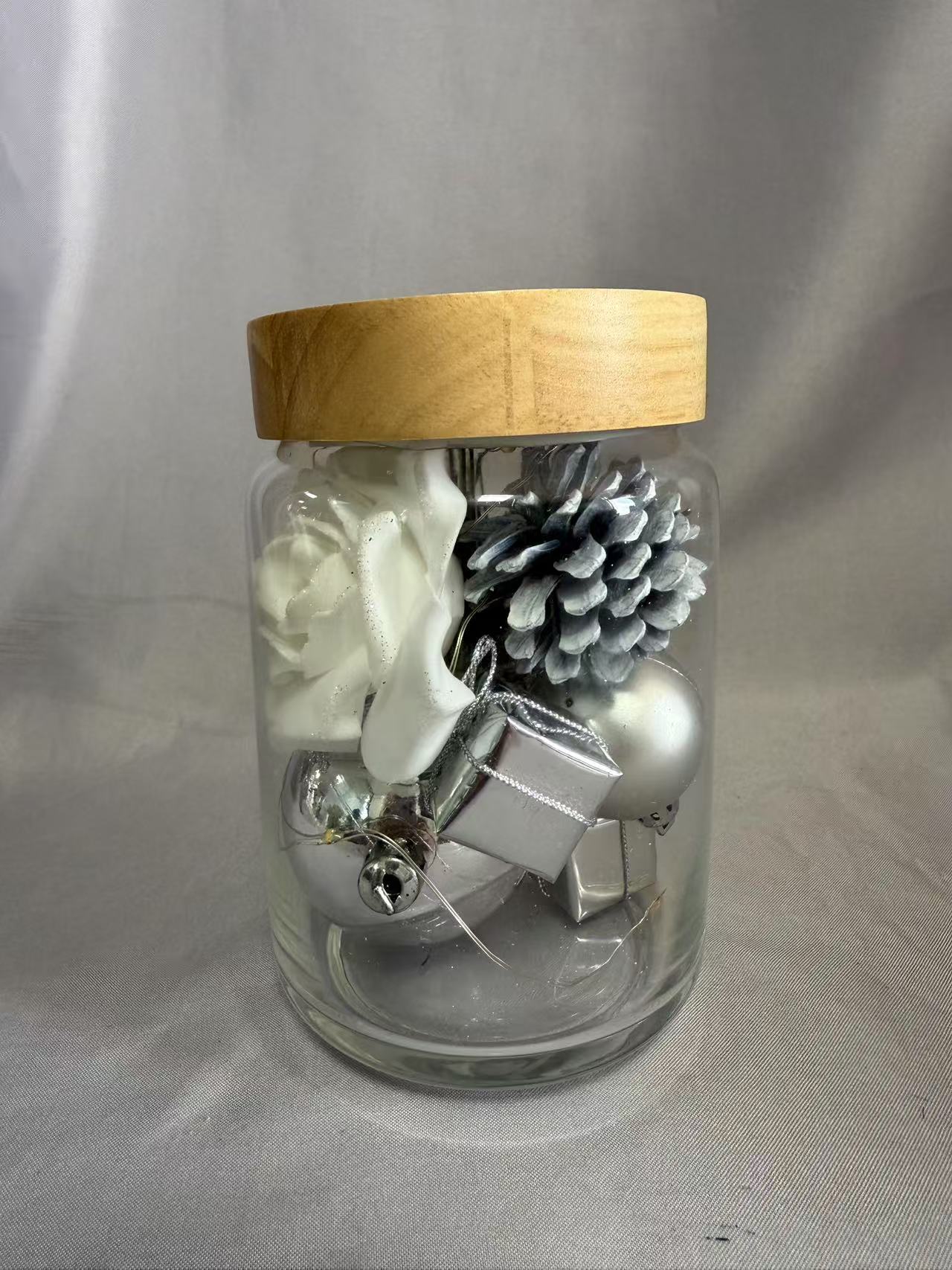 シルバーのトゥインクルワイヤーライトを備えた密閉ガラスジャーの保存された花の花束（AA×2バッテリー駆動）、白いバラ、シルバーベリー、オーブ、ギフトボックス、松ぼっくり、ドライグラスで飾られています